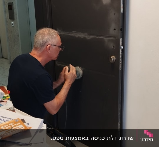 אדם משייף דלת מתכת עם מכשיר חשמלי